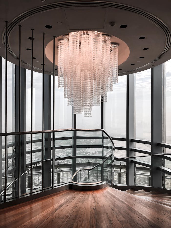 Elegant modern staircase interior featuring a large crystal chandelier and glass walls.